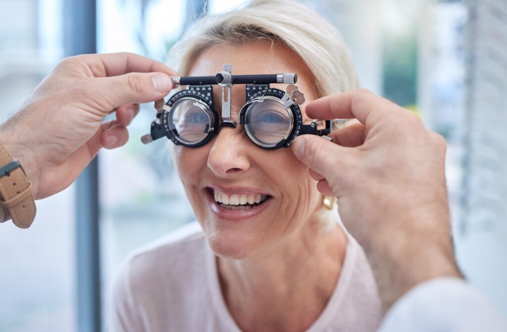  In a brightly lit office space, a patient laughs while their optometrist fits them with a device for an eye test.