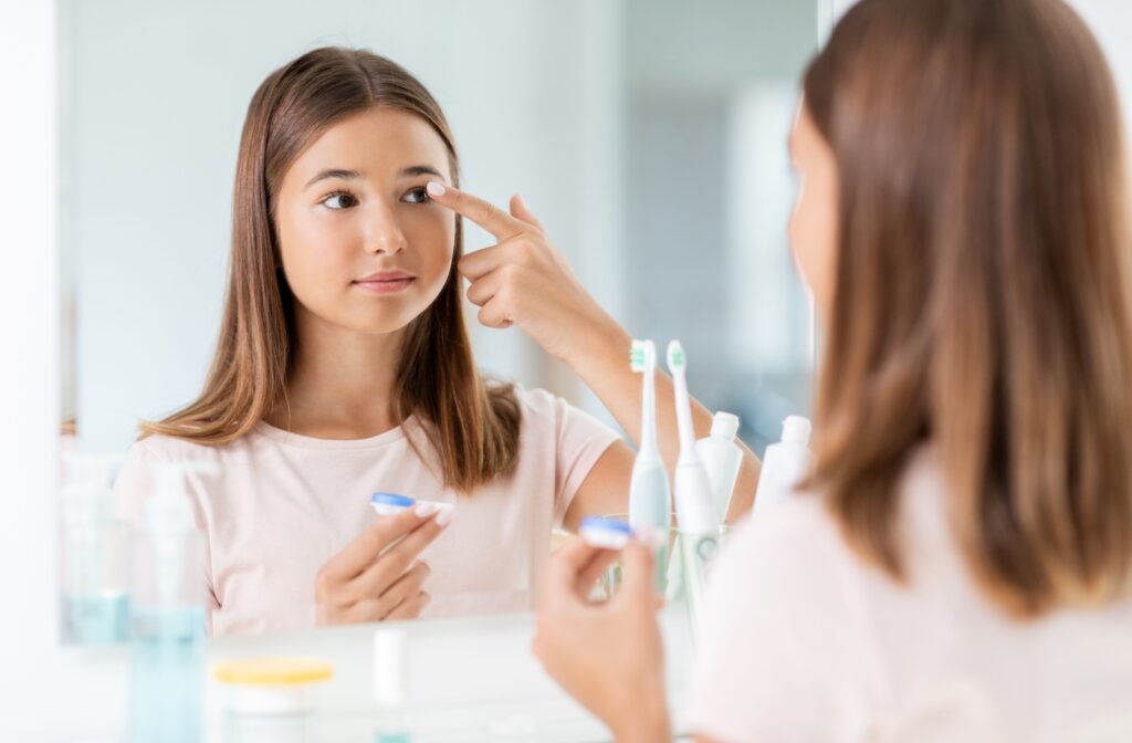 A child puts in their contact lenses using a mirror at home.