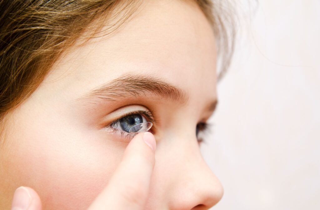 Close-up of a young child carefully putting their contact lens into their eye.