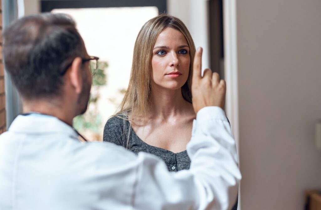 An eye doctor extends his finger in front of a patient during a visual acuity test.