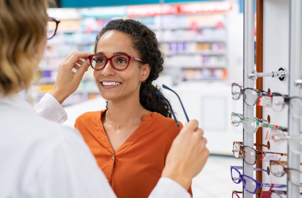 An optometrist helping a patient try on a new pair of glasses