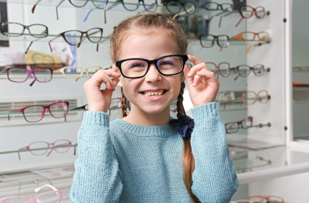 A young child wearing a new pair of glasses, smiling.