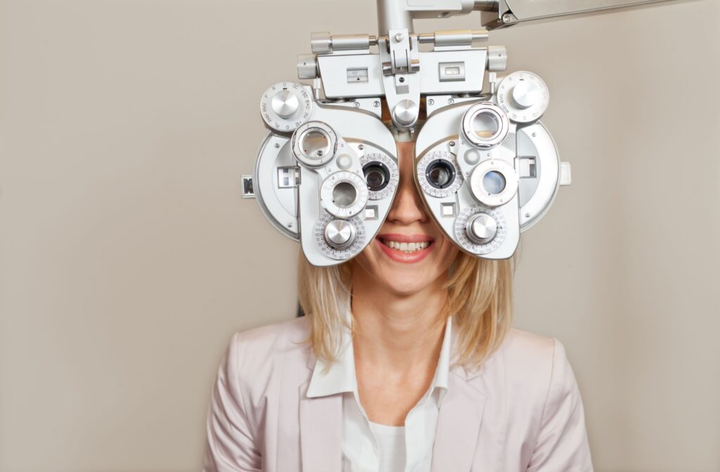 Person undergoing eye exam with phoropter device while smiling in an optometrist’s office.