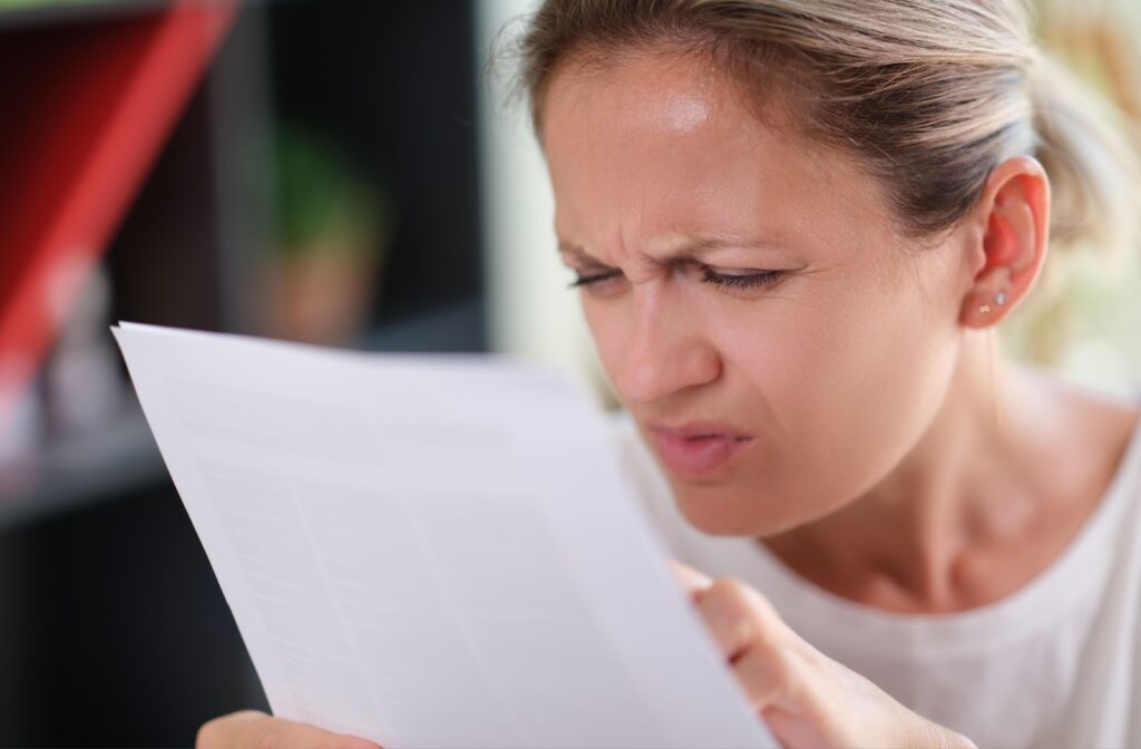 A woman squinting to read the paper that is in front of her face
