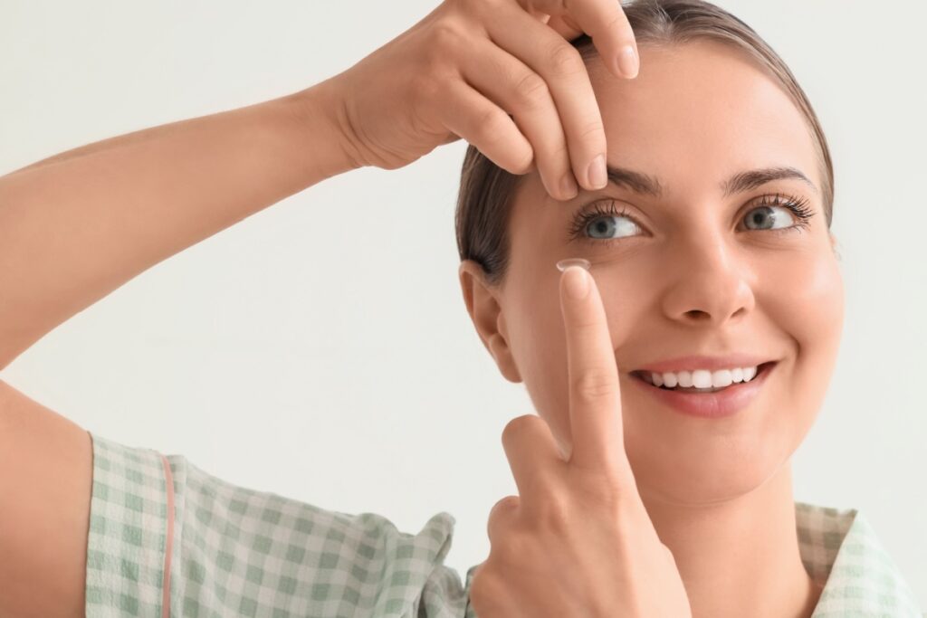 A person using their hand to raise their upper eyelid so they can put a contact lens in their eye